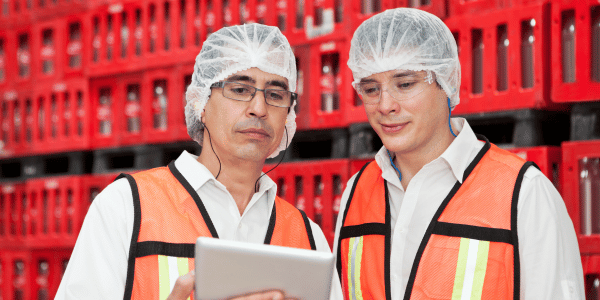 2 personnes dans une usine en train de regarder une tablette tactile.